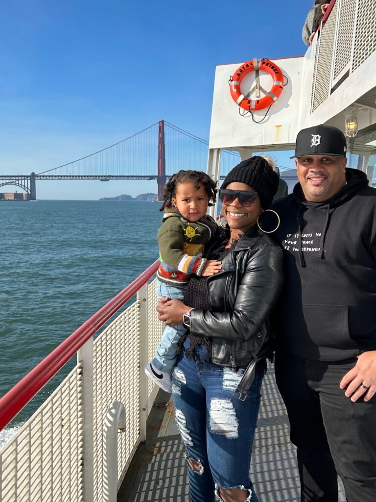 Black Family of 3 on a boat posing in front of the Golden Gate Bridge